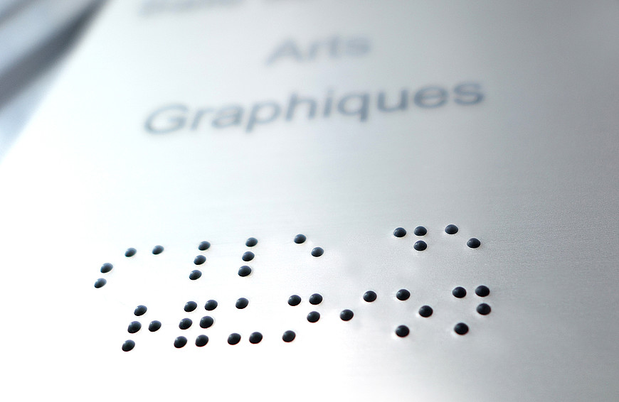 Plaquette métallique indiquant le nom de l'atelier Arts graphiques en braille.